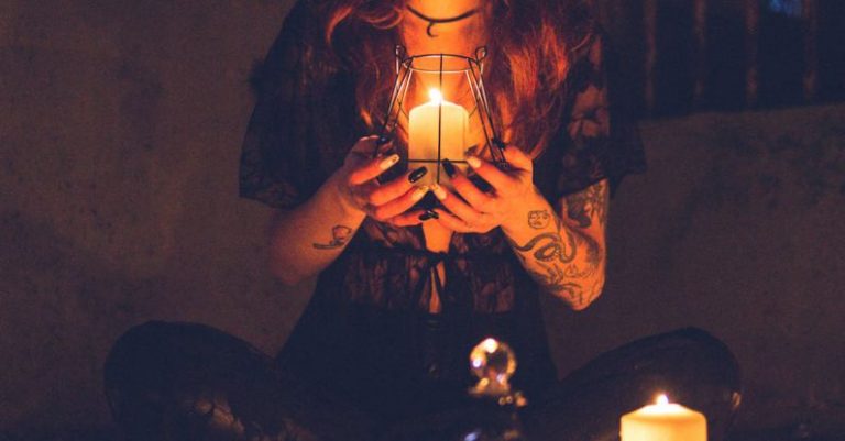 Myths - Spooky witch among candles during ritual