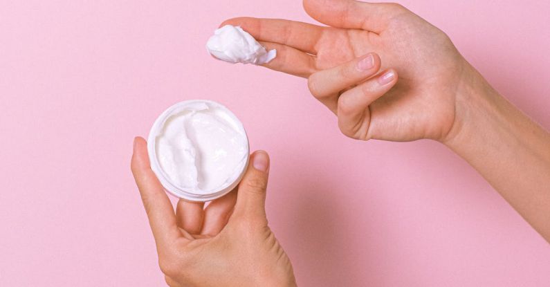 Therapy - Unrecognizable person with can of moisturizing cosmetic cream for daily routine in hands on pink background in studio during procedure